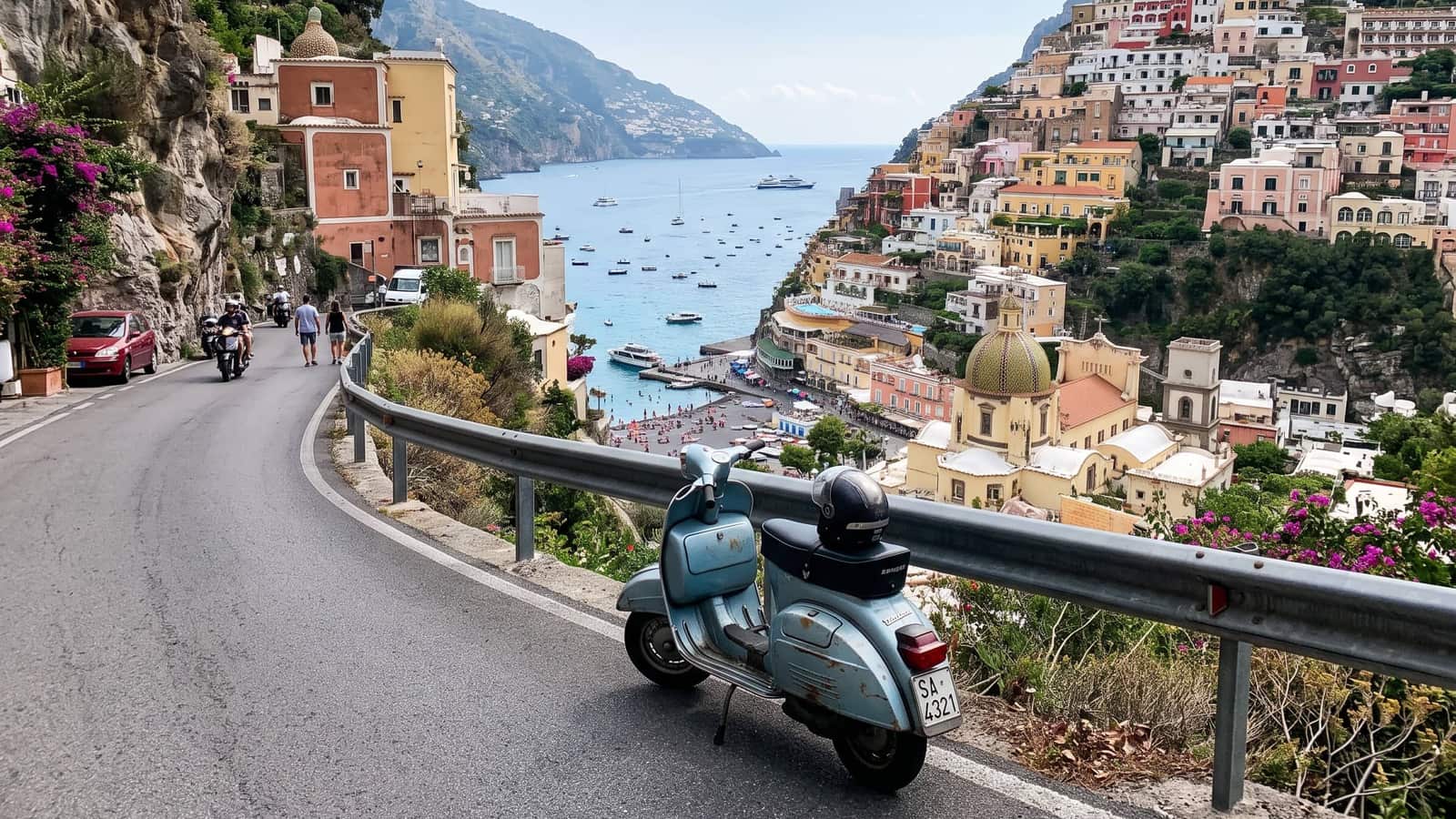 A pale blue scooter parked on a cliff road above a bay of pastel houses and small boats